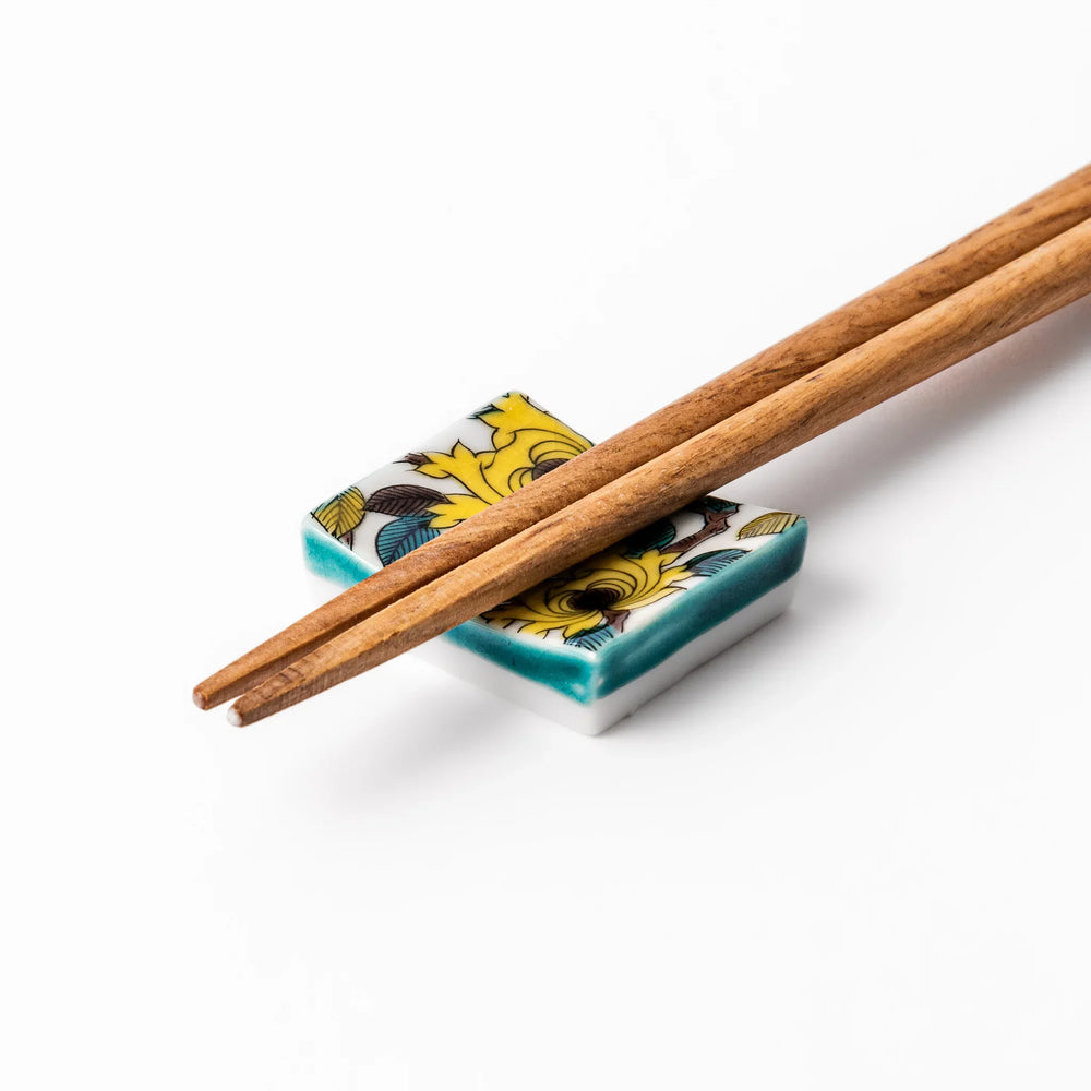 Japanese porcelain chopstick rest with yellow peony and teal leaf motif, hand-painted in traditional Kutani ware style.