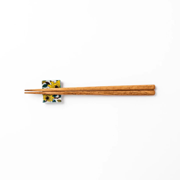 Japanese porcelain chopstick rest with yellow peony and teal leaf motif, hand-painted in traditional Kutani ware style.