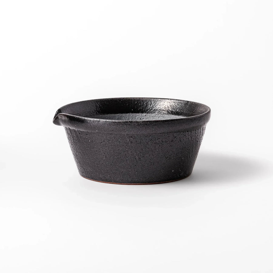 Black Japanese ceramic suribachi bowl with smooth interior and spout for grinding or mixing easy cleanup.