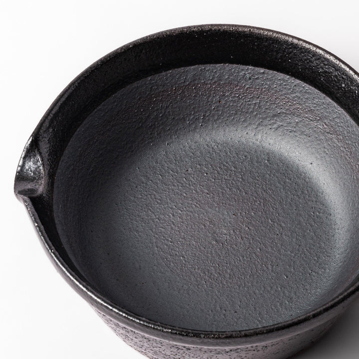 Black Japanese ceramic suribachi bowl with smooth interior and spout for grinding or mixing easy cleanup.