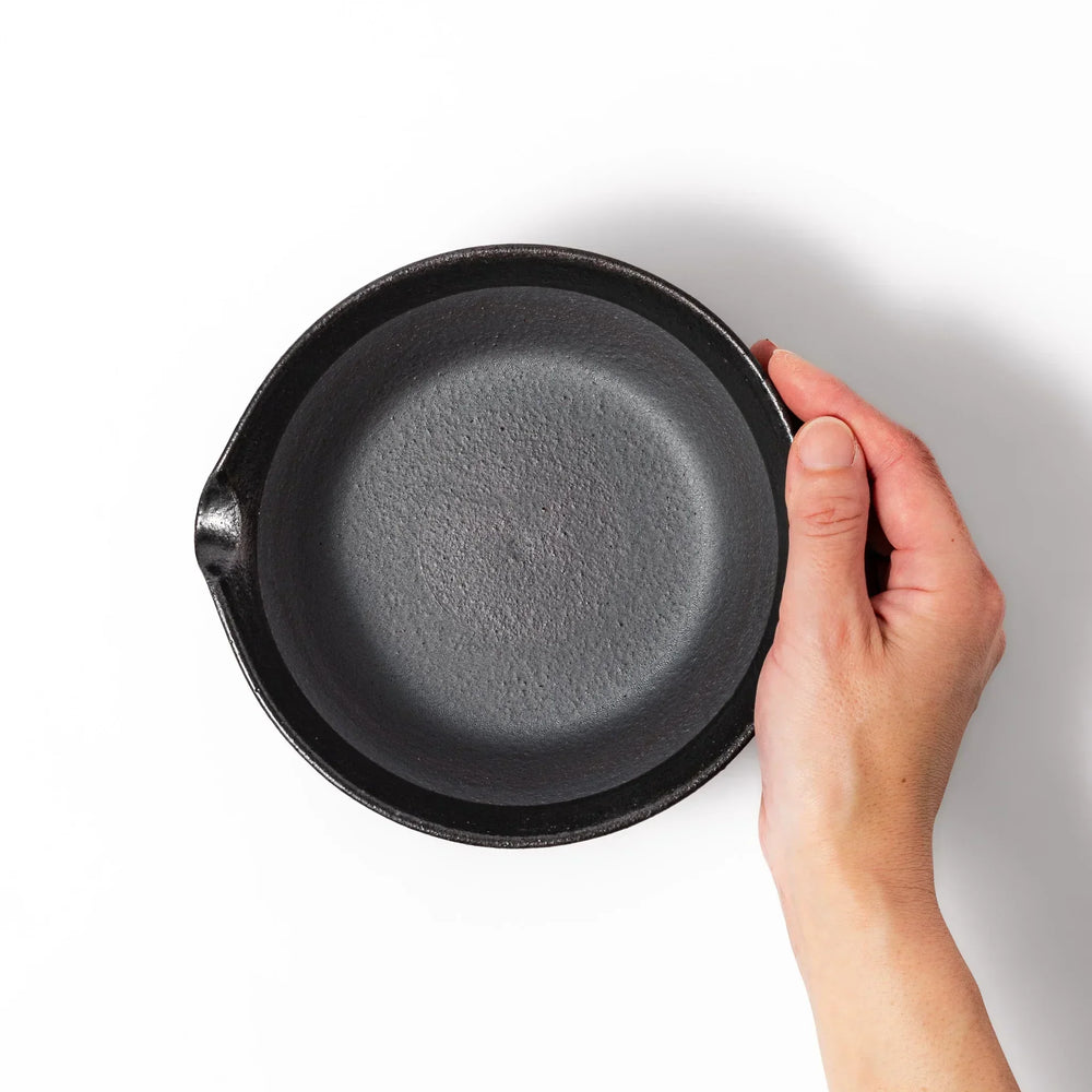 Black Japanese ceramic suribachi bowl with smooth interior and spout for grinding or mixing easy cleanup.
