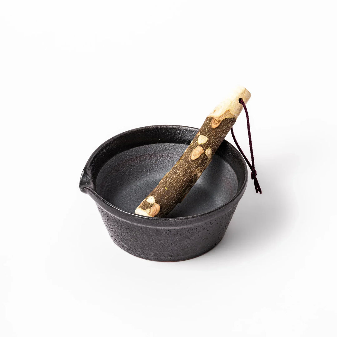 Black Japanese ceramic suribachi mortar bowl with smooth interior and spout for grinding or easy mixing.