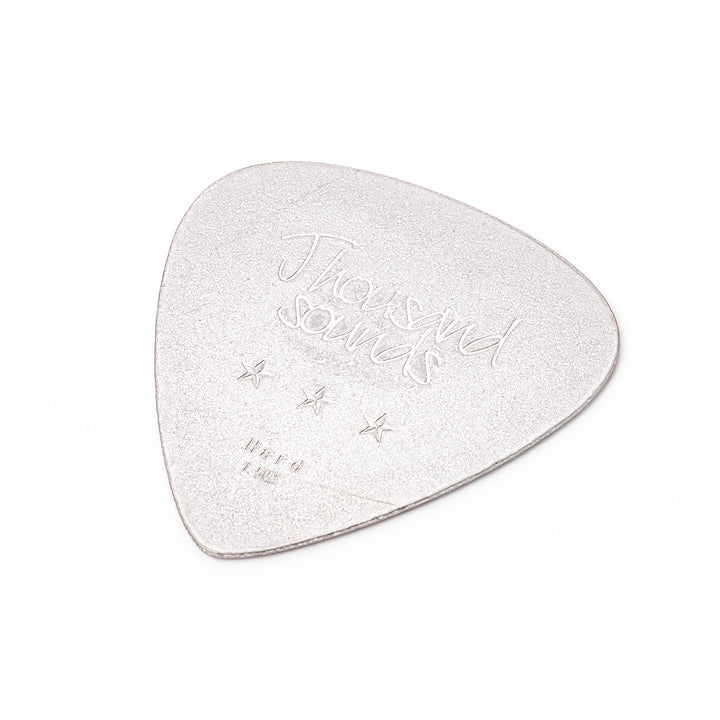 Unique guitar pick shaped metal coaster with sandblasted textured finish engraved with thousand sounds text and stars