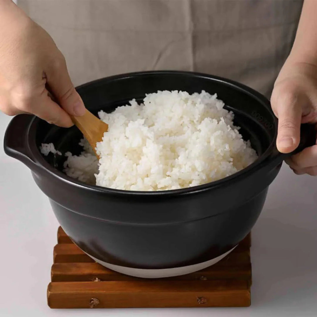 Fluffing cooked white rice with wooden spatula inside hario glass lid donabe clay pot cooker kitchenware