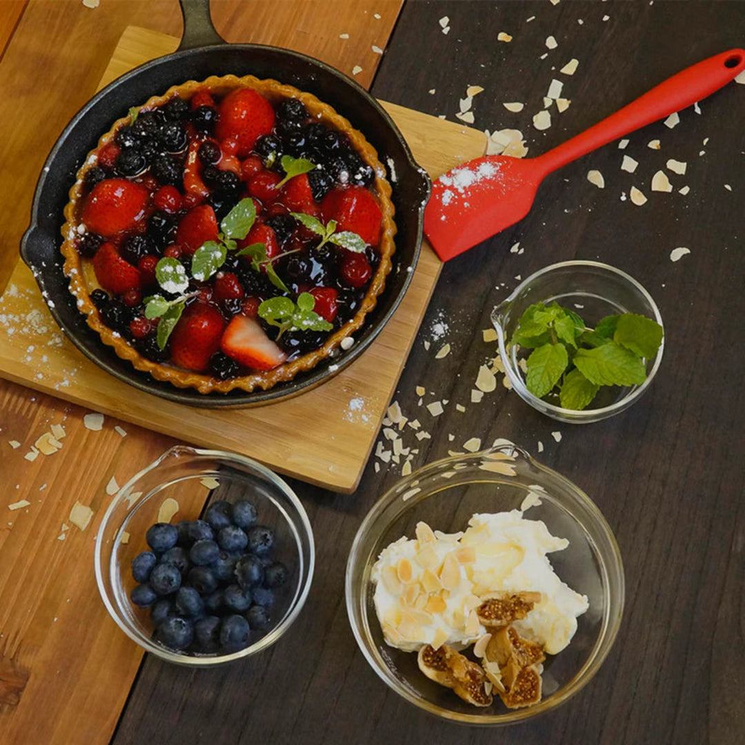 Preparing a berry tart next to hario heatproof glass lip bowls filled with blueberries mint leaves and cream dessert