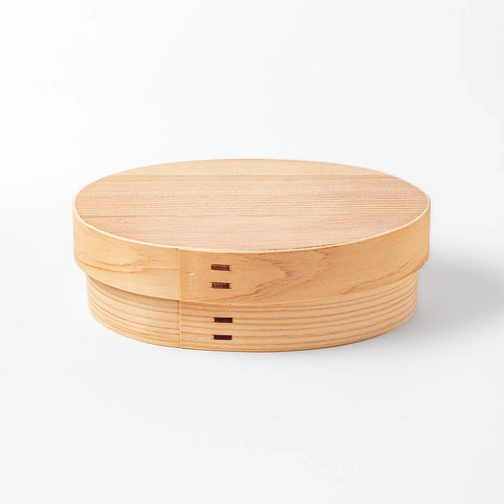 Oval Japanese hinoki wood bento box with traditional joinery for carrying light aromatic homemade meals.
