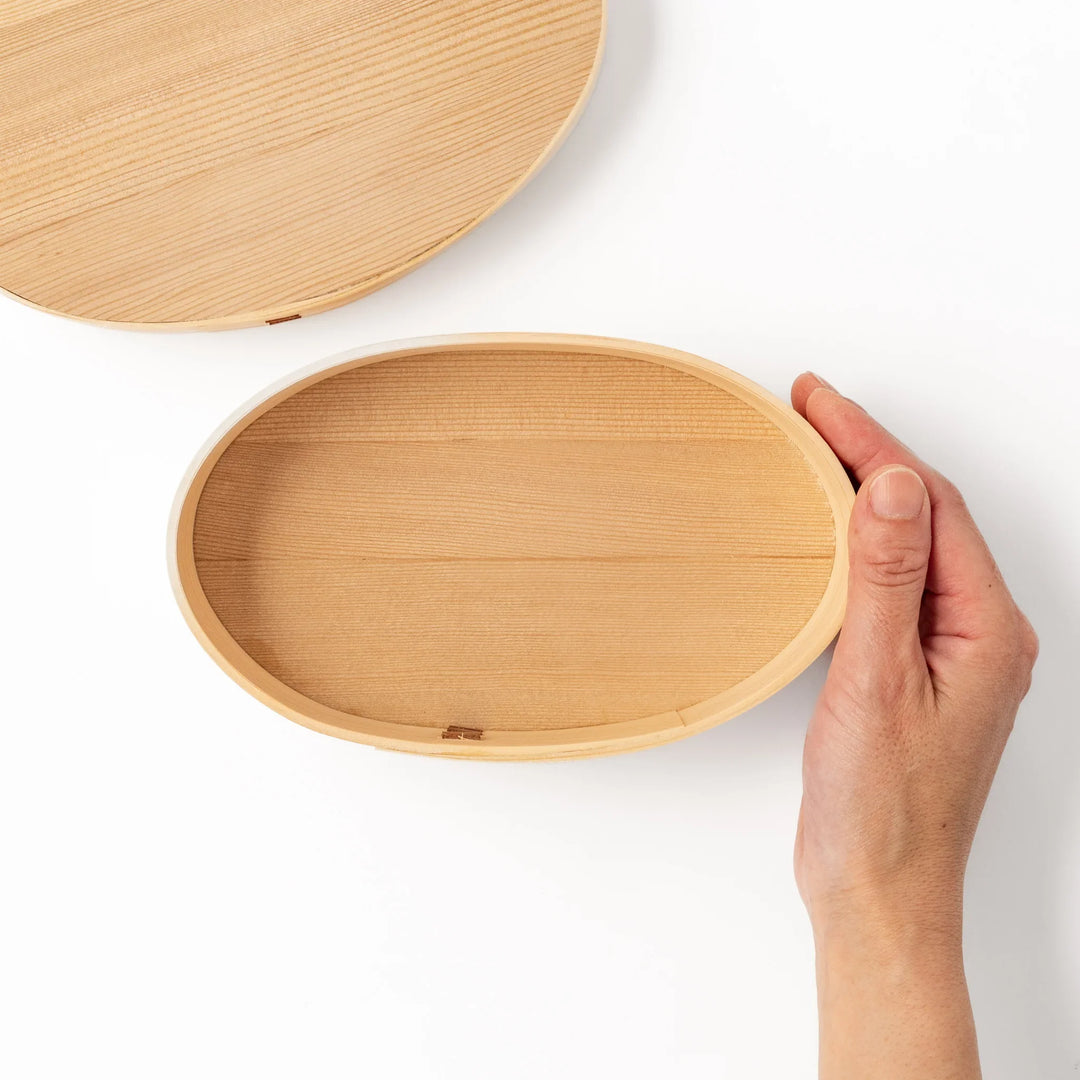 Oval Japanese hinoki wood bento box with traditional joinery for carrying light aromatic homemade meals.