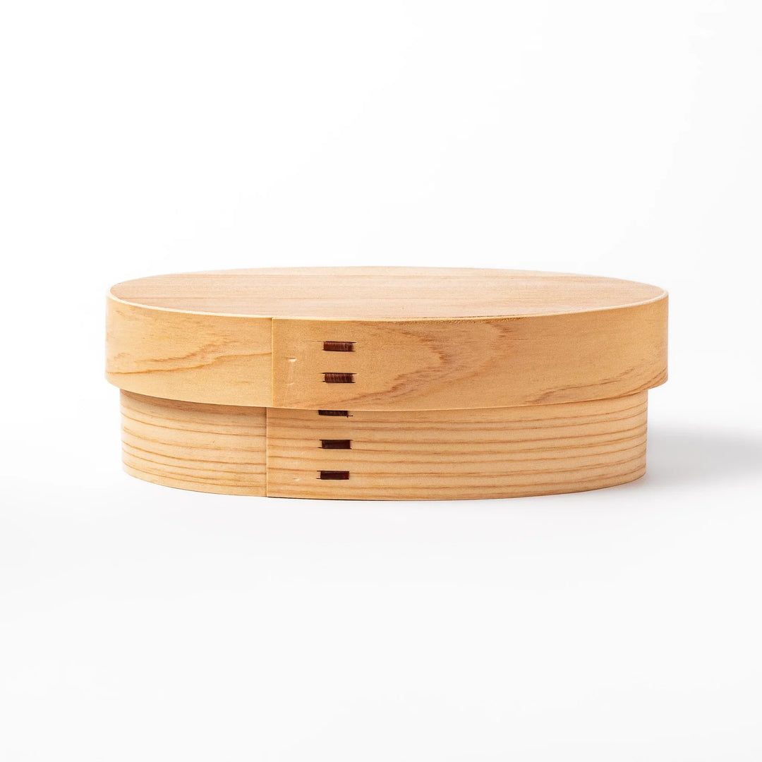 Oval Japanese hinoki wood bento box with traditional joinery for carrying light aromatic homemade meals.
