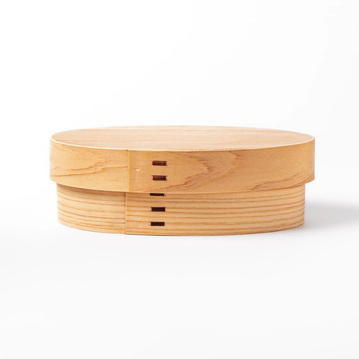Oval Japanese hinoki wood bento box with traditional joinery for carrying light aromatic homemade meals.