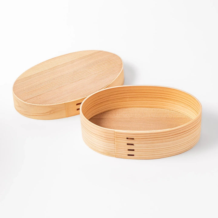Oval Japanese hinoki wood bento box with traditional joinery for carrying light aromatic homemade meals.