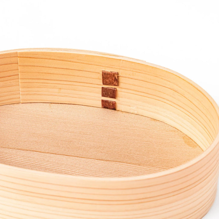 Oval Japanese hinoki wood bento box with traditional joinery for carrying light aromatic homemade meals.