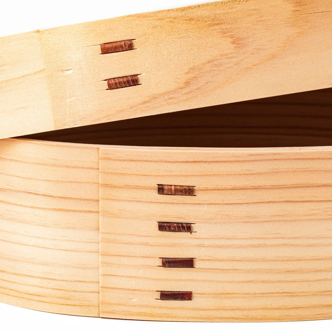 Oval Japanese hinoki wood bento box with traditional joinery for carrying light aromatic homemade meals.