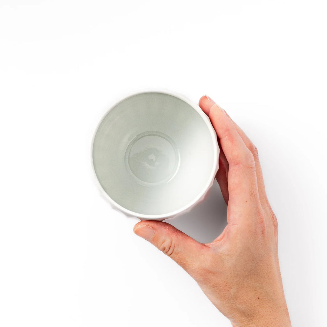 White teacup with vertical petal grooves and glossy finish perfect for serving hot tea in modern style.
