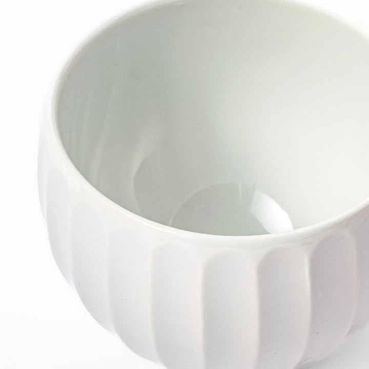 White teacup with vertical petal grooves and glossy finish perfect for serving hot tea in modern style.
