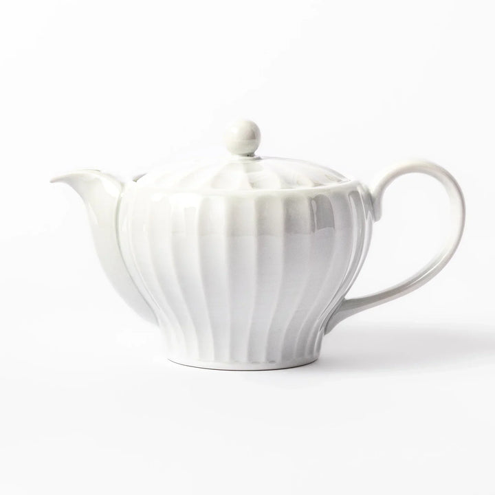 White teapot with vertical petal-inspired ridges and a round lid, perfect for a refined and elegant tea presentation.