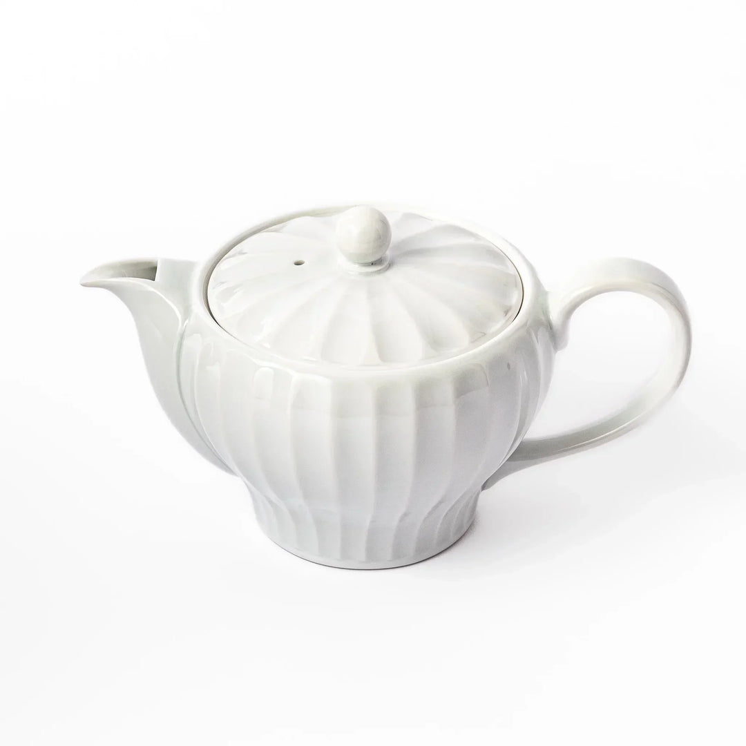 White teapot with vertical petal-inspired ridges and a round lid, perfect for a refined and elegant tea presentation.