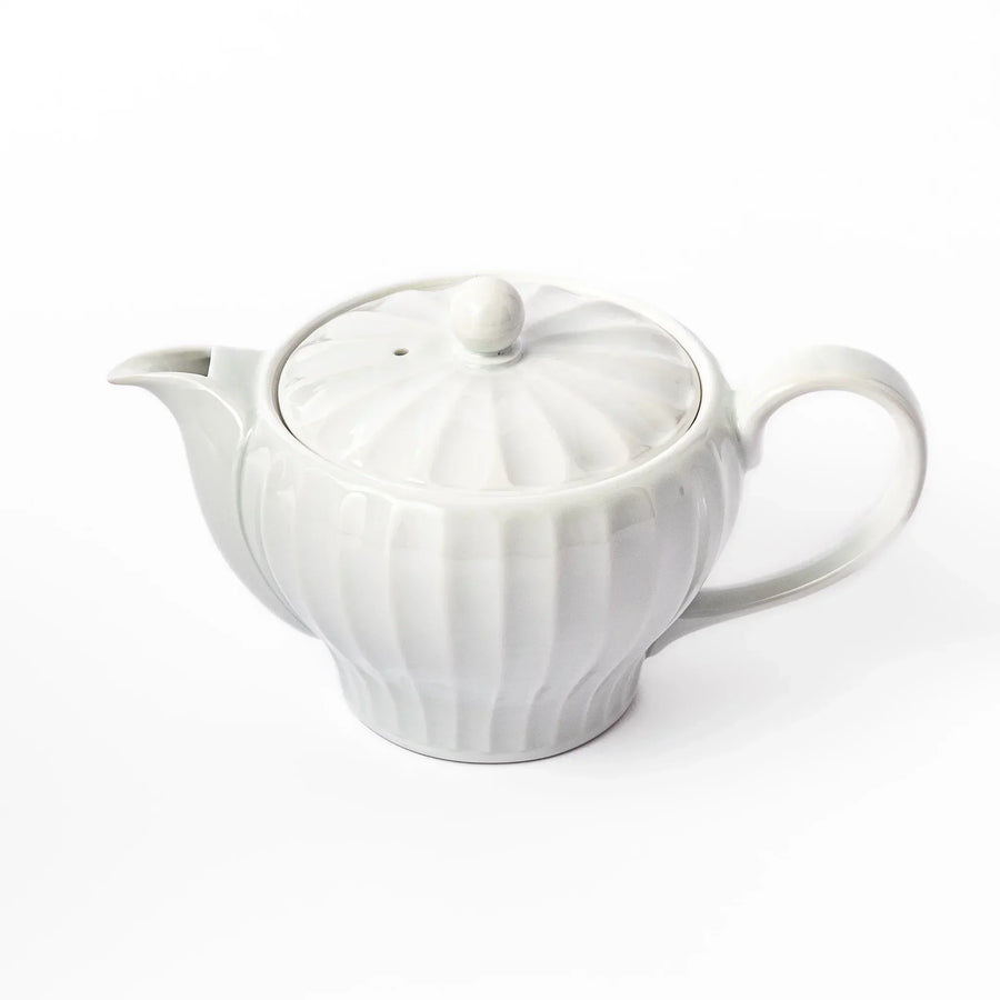 White teapot with vertical petal-inspired ridges and a round lid, perfect for a refined and elegant tea presentation.