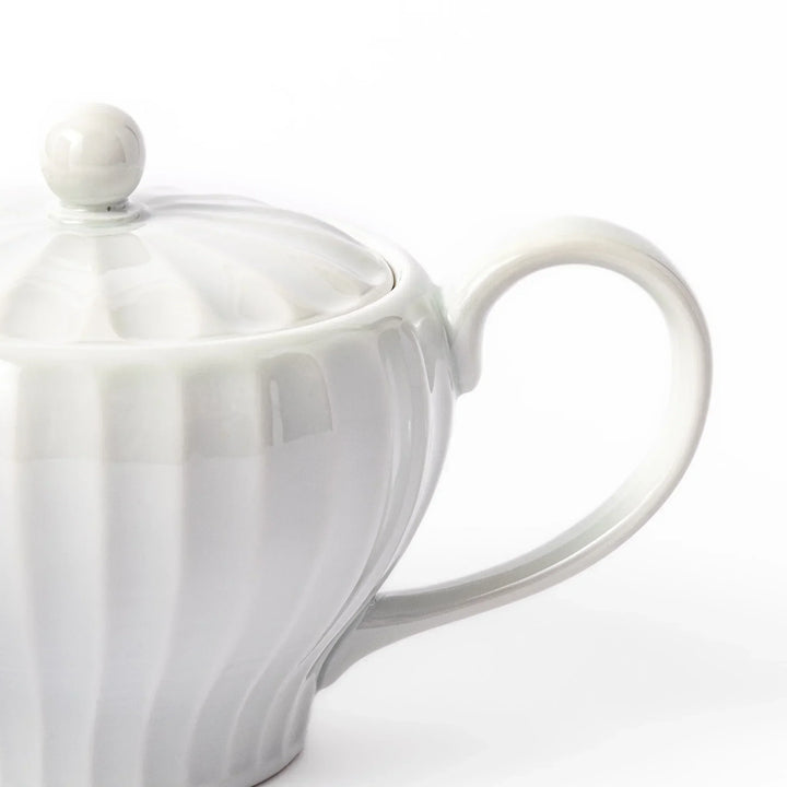 White teapot with vertical petal-inspired ridges and a round lid, perfect for a refined and elegant tea presentation.