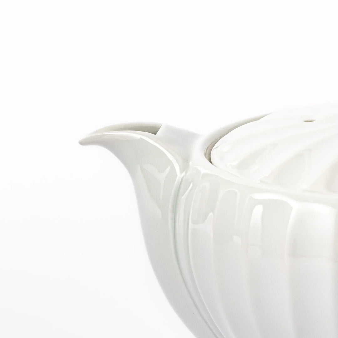 White teapot with vertical petal-inspired ridges and a round lid, perfect for a refined and elegant tea presentation.