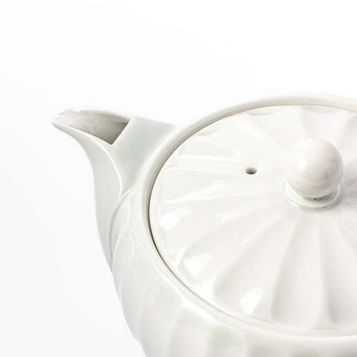 White teapot with vertical petal-inspired ridges and a round lid, perfect for a refined and elegant tea presentation.