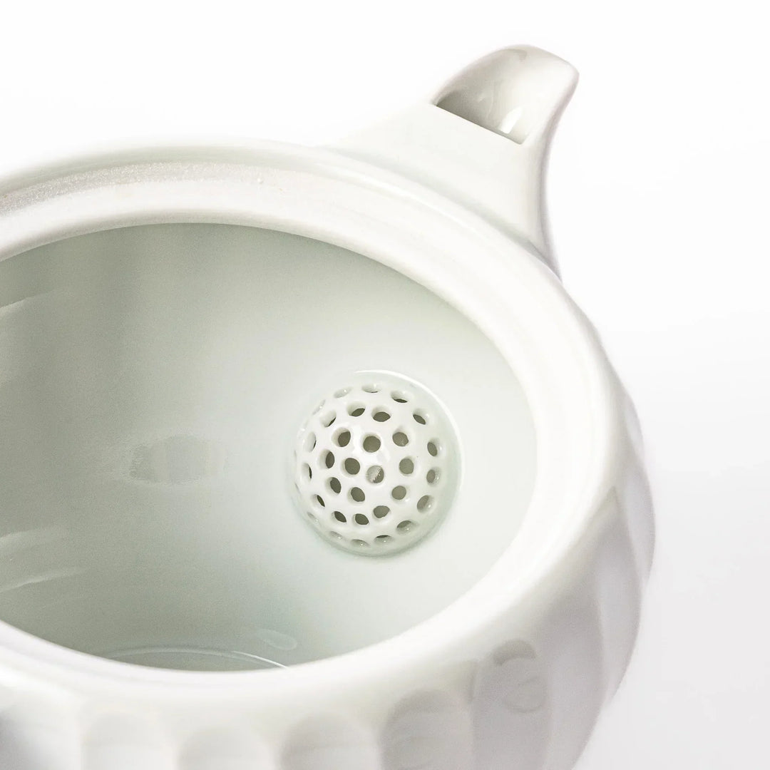 White teapot with vertical petal-inspired ridges and a round lid, perfect for a refined and elegant tea presentation.