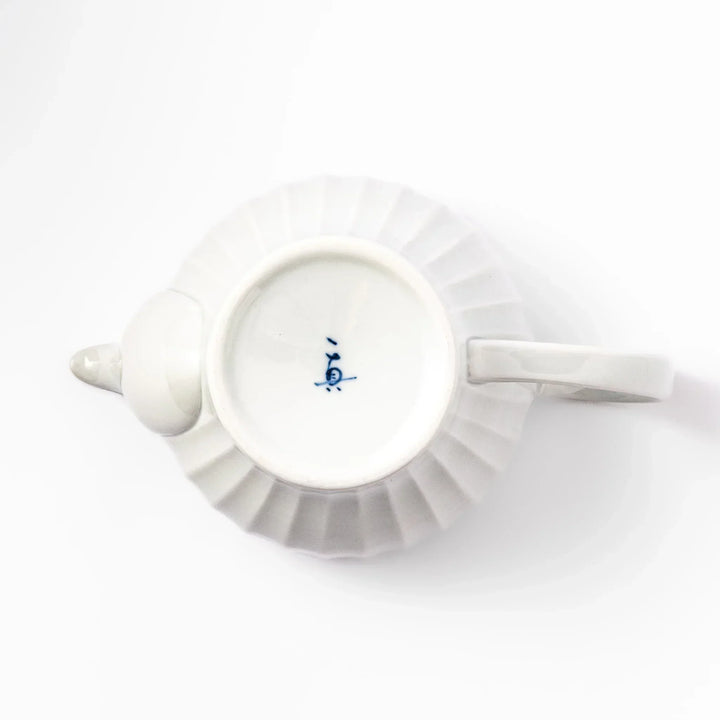 White teapot with vertical petal-inspired ridges and a round lid, perfect for a refined and elegant tea presentation.