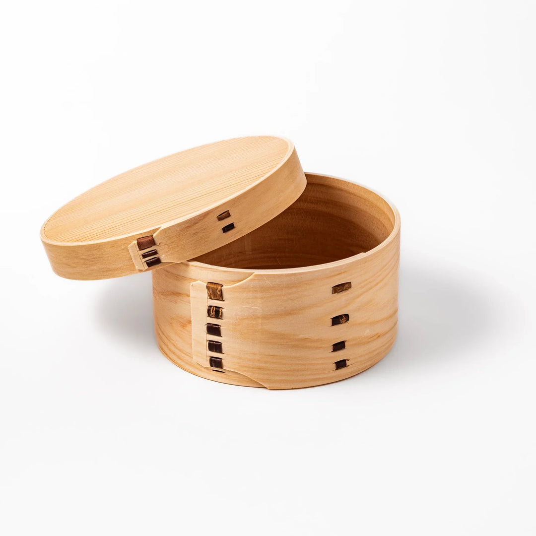 Oval Japanese hinoki wood bento box with traditional joinery for carrying light aromatic homemade meals.