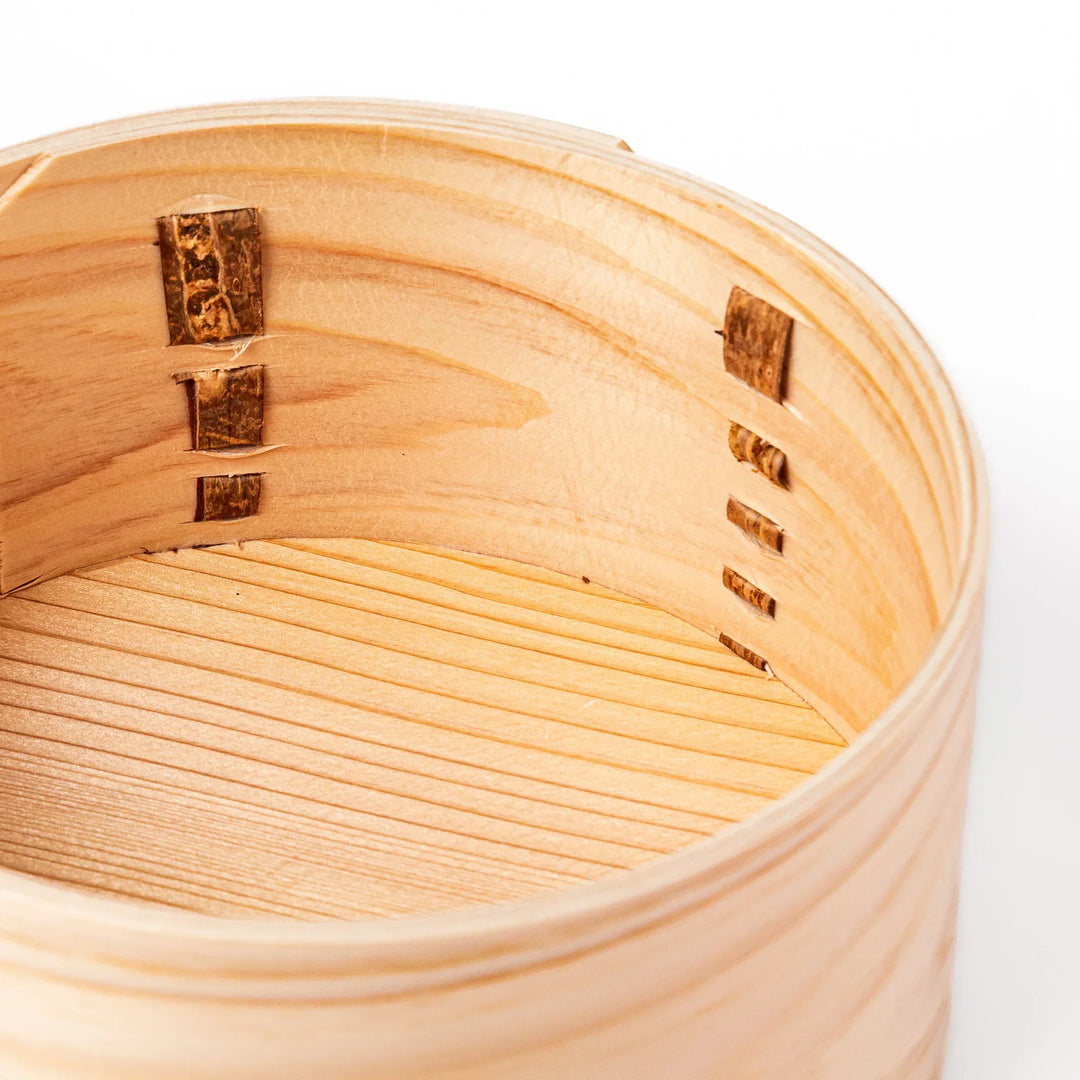 Oval Japanese hinoki wood bento box with traditional joinery for carrying light aromatic homemade meals.