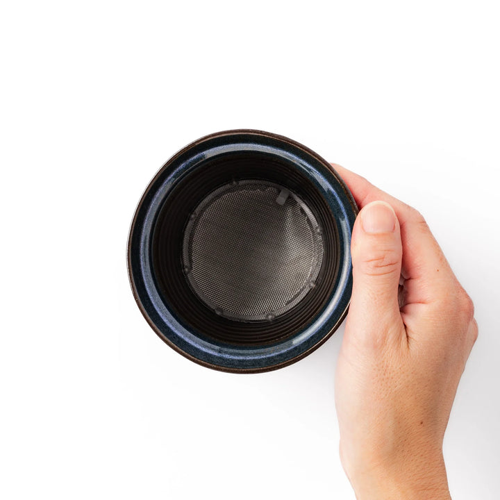 Handcrafted ceramic coffee dripper in brown and blue glaze with mesh filter for single serve brewing.