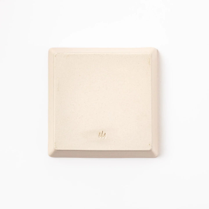 Square beige plate featuring a playful black cat chasing a butterfly, with paw prints and a dotted flight path.