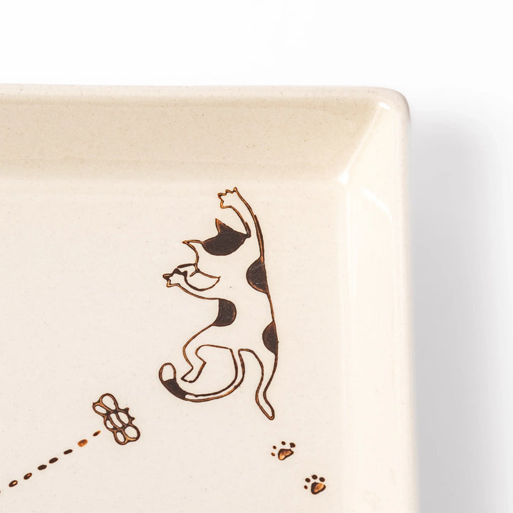 Beige square plate with playful calico cat and butterfly illustration, accented with dotted lines and paw prints.