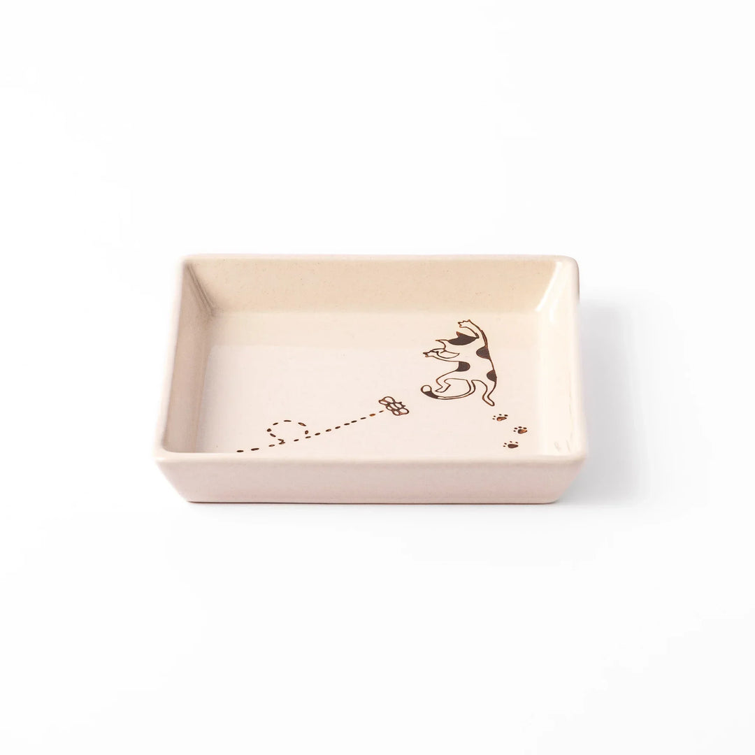 Beige square plate with playful calico cat and butterfly illustration, accented with dotted lines and paw prints.