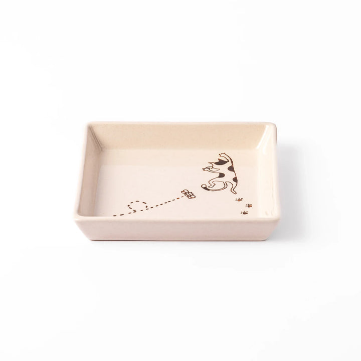 Beige square plate with playful calico cat and butterfly illustration, accented with dotted lines and paw prints.