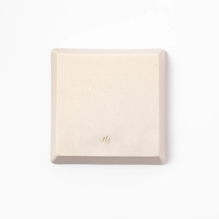 Beige square plate with playful calico cat and butterfly illustration, accented with dotted lines and paw prints.