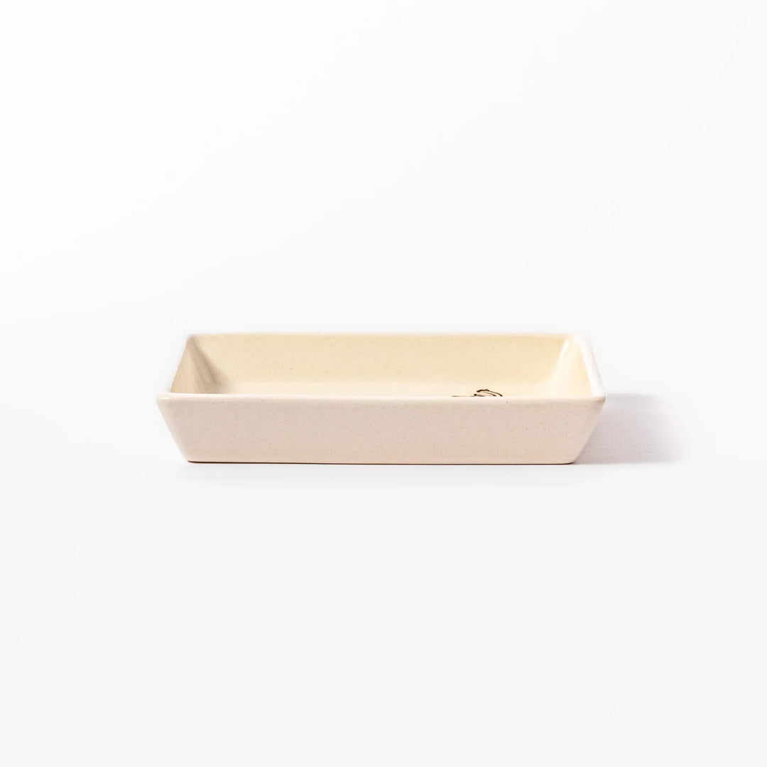 Beige square plate featuring a tabby cat chasing a butterfly with dotted trail and small paw prints.