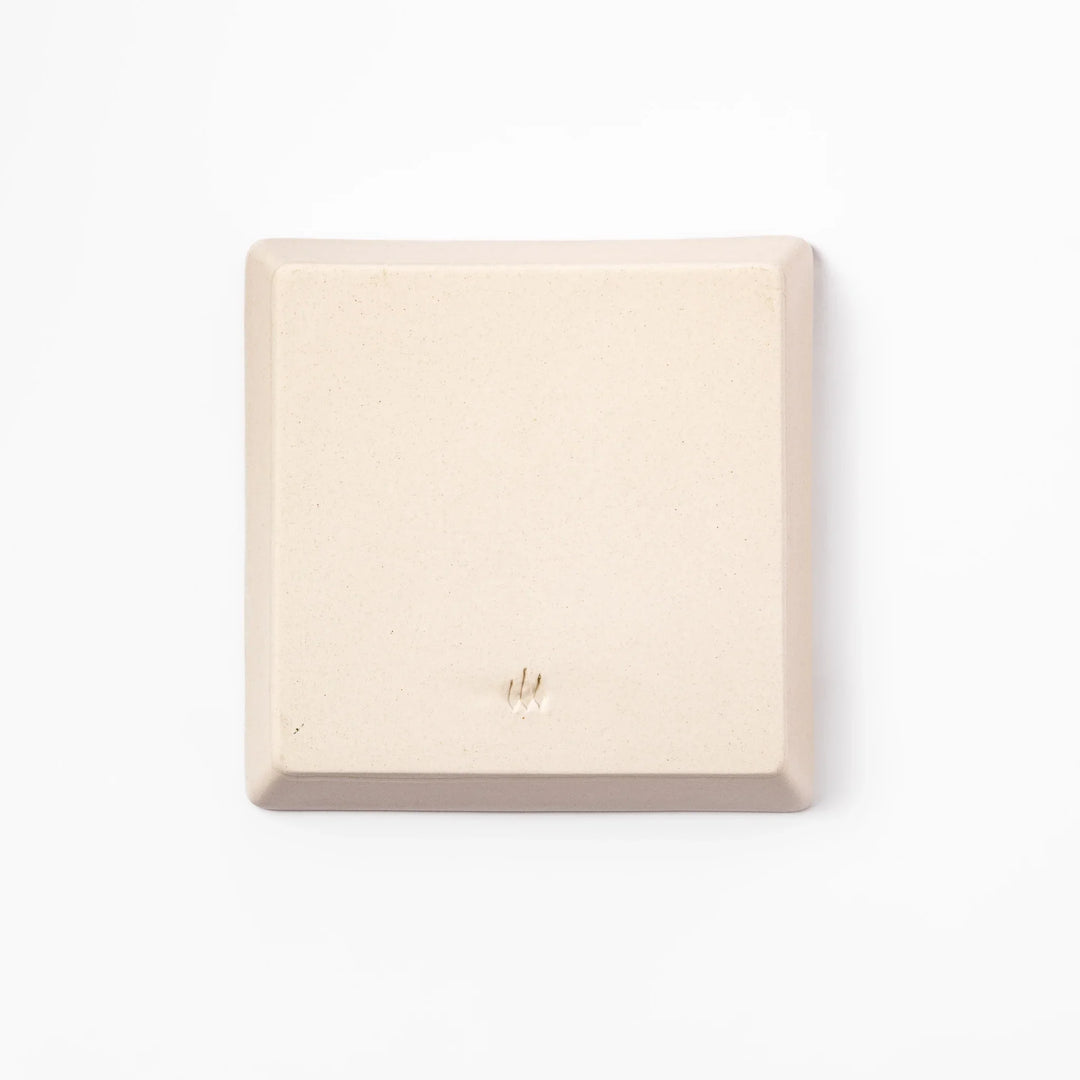 Beige square plate featuring a tabby cat chasing a butterfly with dotted trail and small paw prints.