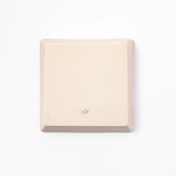 Beige square plate featuring a tabby cat chasing a butterfly with dotted trail and small paw prints.