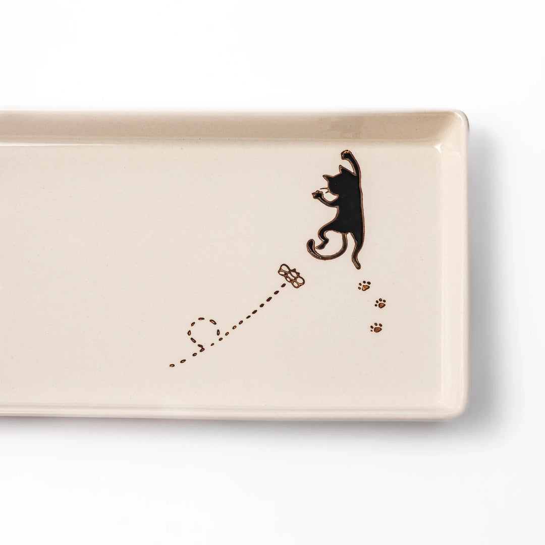 Beige rectangular ceramic plate featuring a playful black cat illustration with paw prints and a butterfly in the corner.