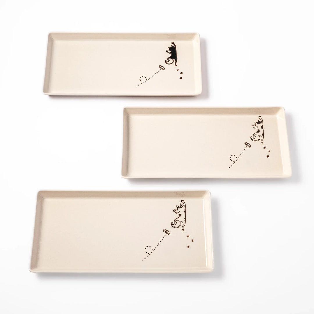 Set of beige rectangular ceramic plates with black calico and tabby cat illustrations paw prints and butterflies.