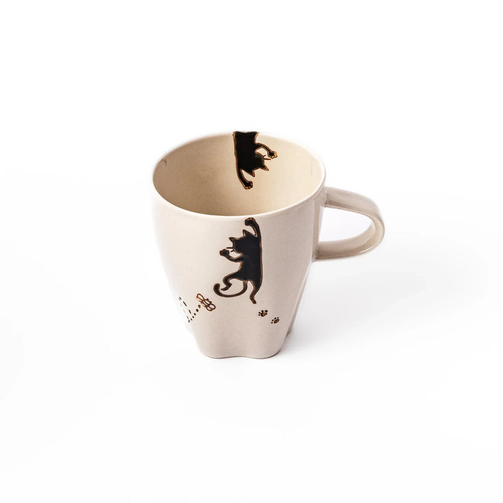 Cream-colored cup with a black cat design reaching for a butterfly, accented by playful dotted lines and paw prints.