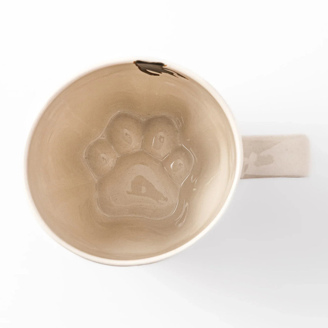 Cream-colored cup with a black cat design reaching for a butterfly, accented by playful dotted lines and paw prints.