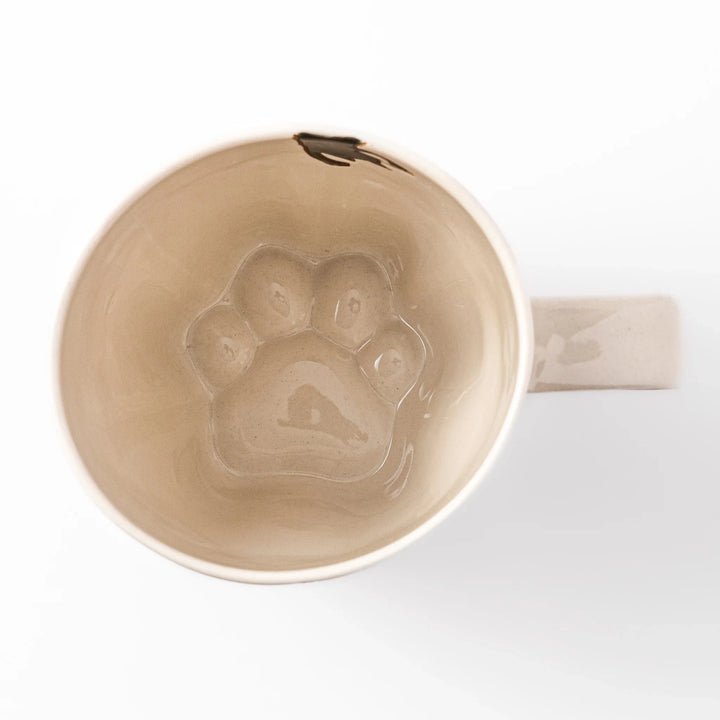 Cream-colored cup with a black cat design reaching for a butterfly, accented by playful dotted lines and paw prints.