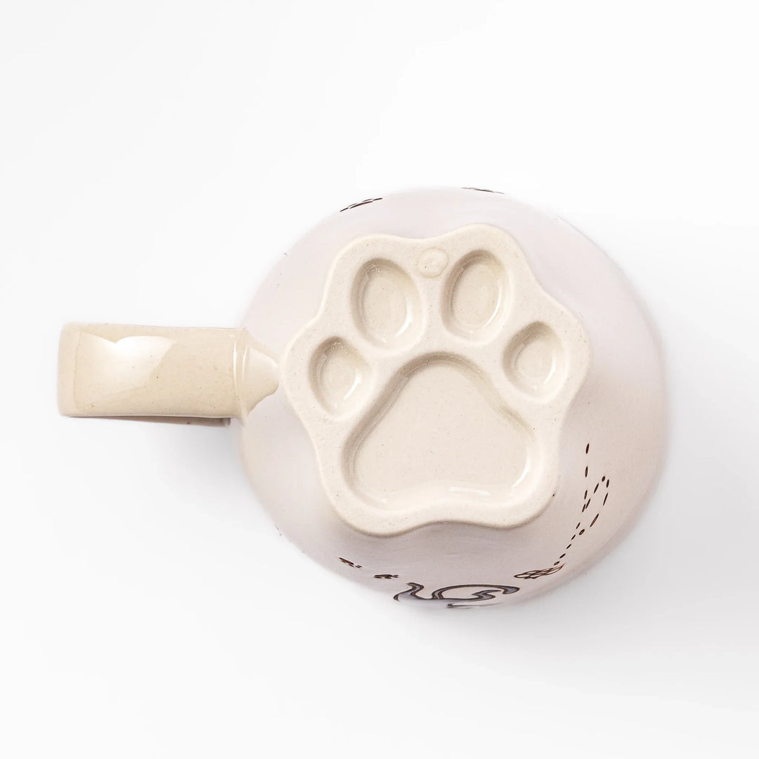Cream-colored cup with a black cat design reaching for a butterfly, accented by playful dotted lines and paw prints.