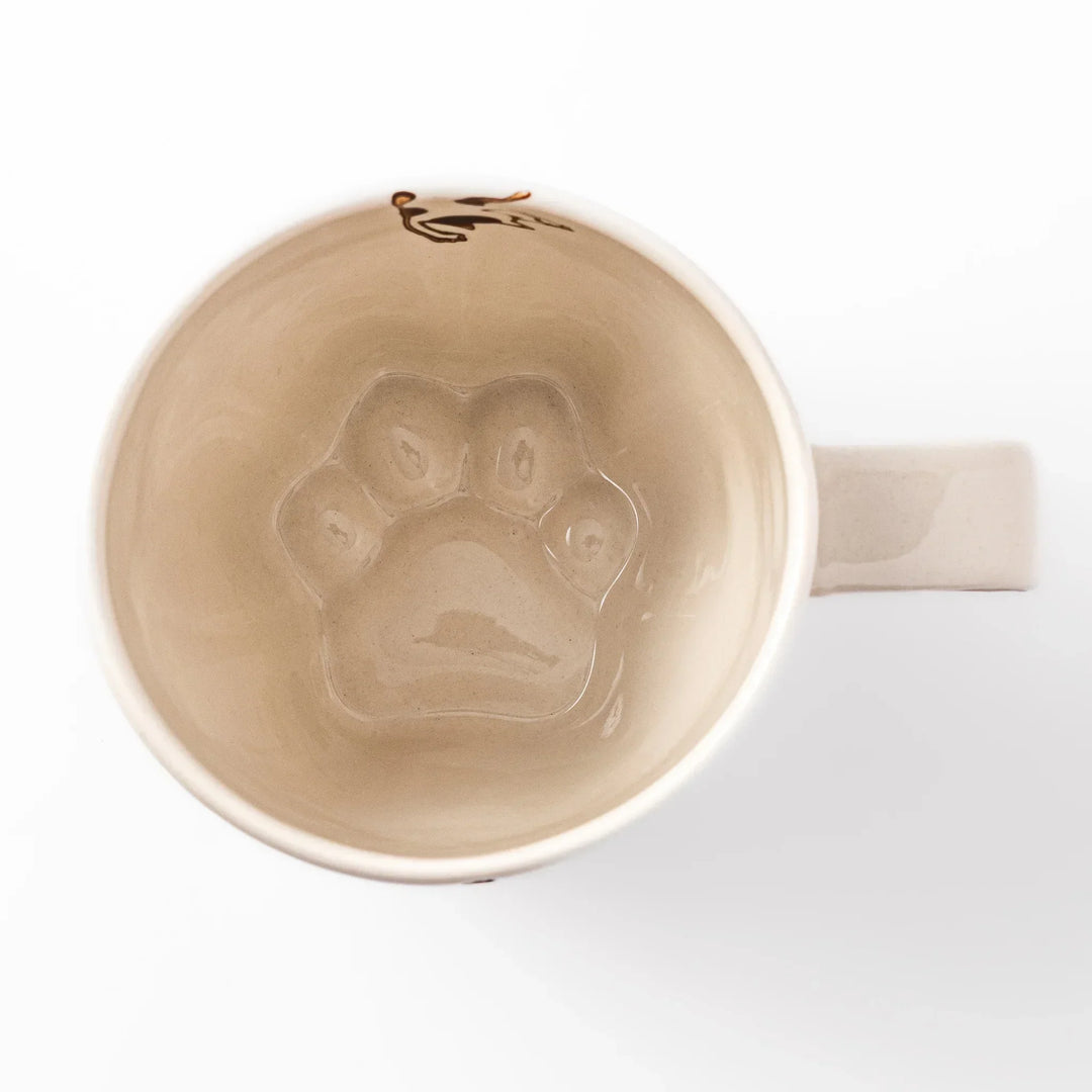 Cream-colored cup with a calico cat design reaching for a butterfly, decorated with dotted lines and paw prints.