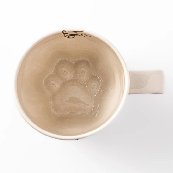 Cream-colored cup with a calico cat design reaching for a butterfly, decorated with dotted lines and paw prints.