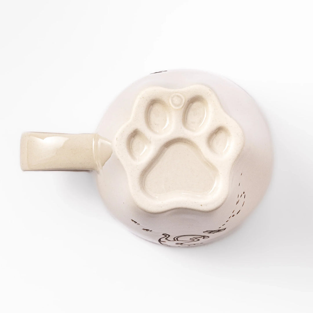 Cream-colored cup with a striped cat design reaching toward a butterfly, with dotted lines and paw prints.