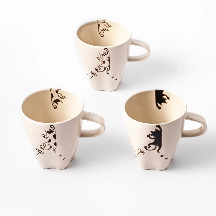 Three cream-colored cups each with a different hanging cat design and butterfly, featuring paw prints and curved lines.