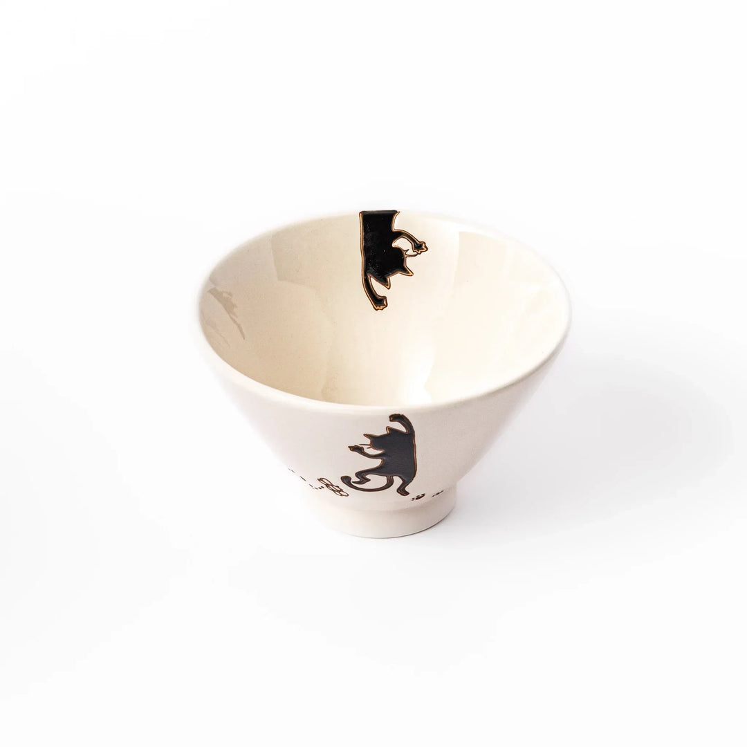 Cream-colored rice bowl with a black hanging cat, butterfly, and playful paw prints on the outside and inner rim.