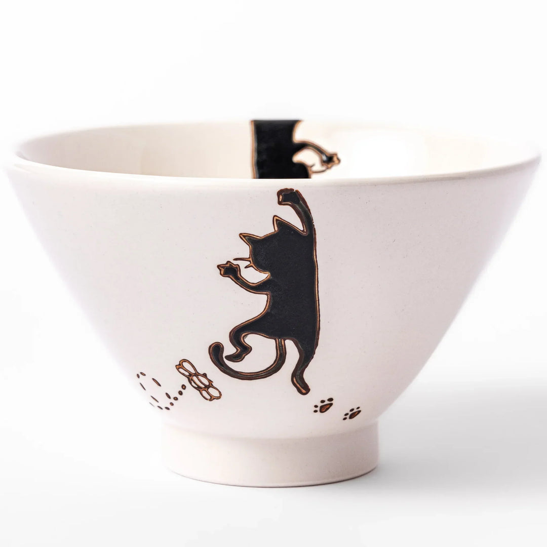 Cream-colored rice bowl with a black hanging cat, butterfly, and playful paw prints on the outside and inner rim.