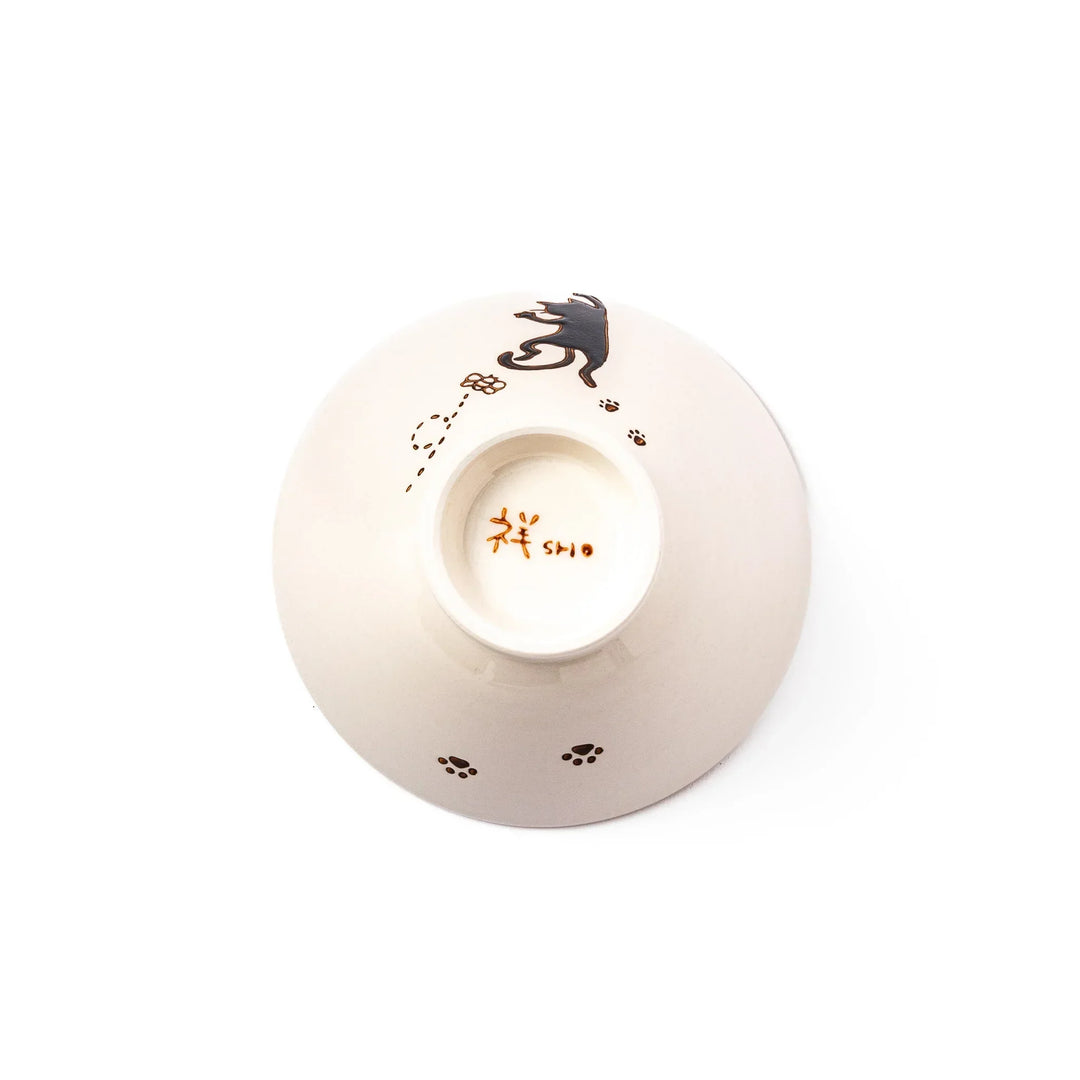 Cream-colored rice bowl with a black hanging cat, butterfly, and playful paw prints on the outside and inner rim.